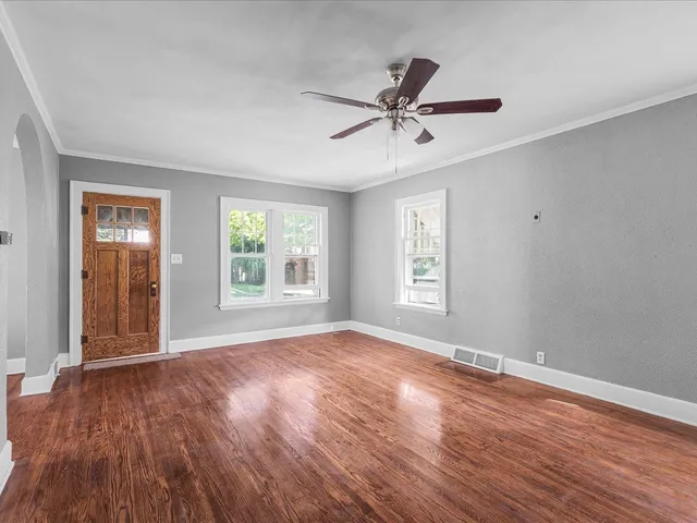 a view of empty room with wooden floor and fan
