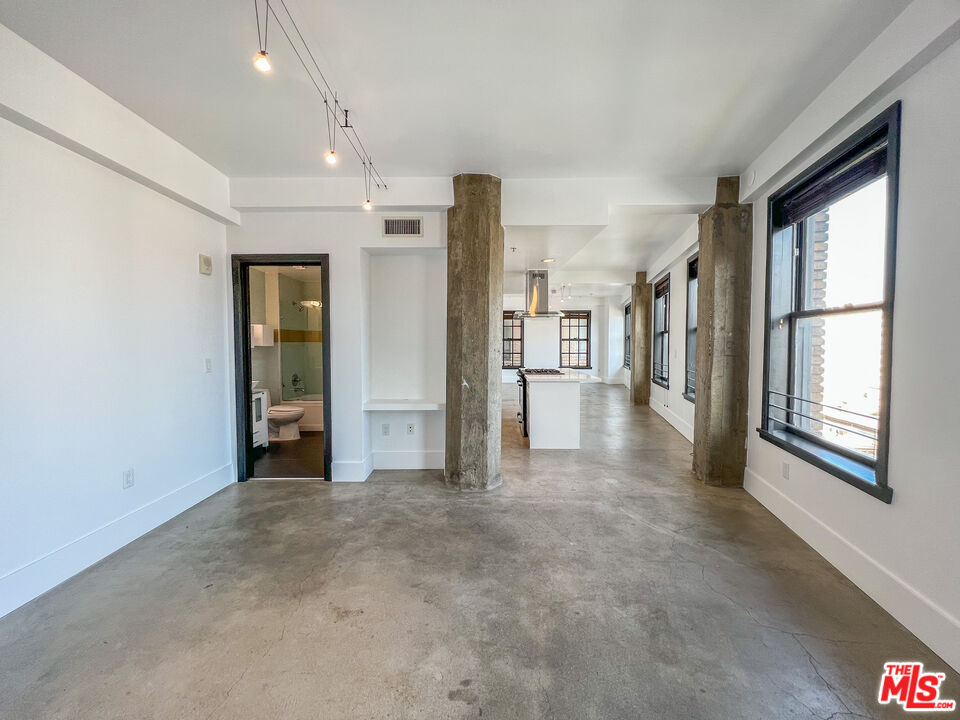 810 South Spring Street, Unit 802 Los Angeles, CA 90014 - Photo 7 of 18 a view of empty room with floor to ceiling window and refrigerator