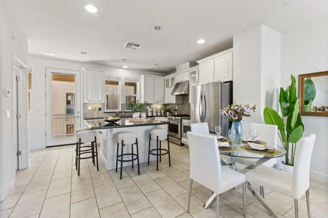 a kitchen with a dining table chairs and refrigerator