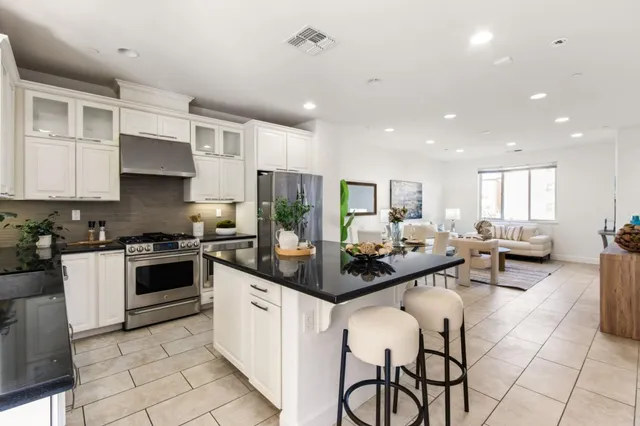a kitchen with stainless steel appliances kitchen island granite countertop a stove and white cabinets