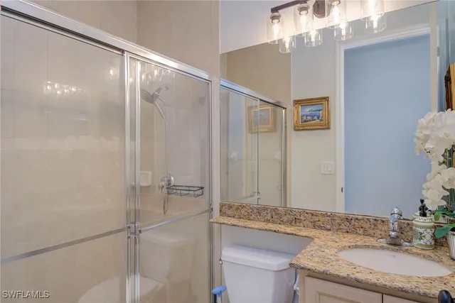 a bathroom with a granite countertop sink a mirror and a shower