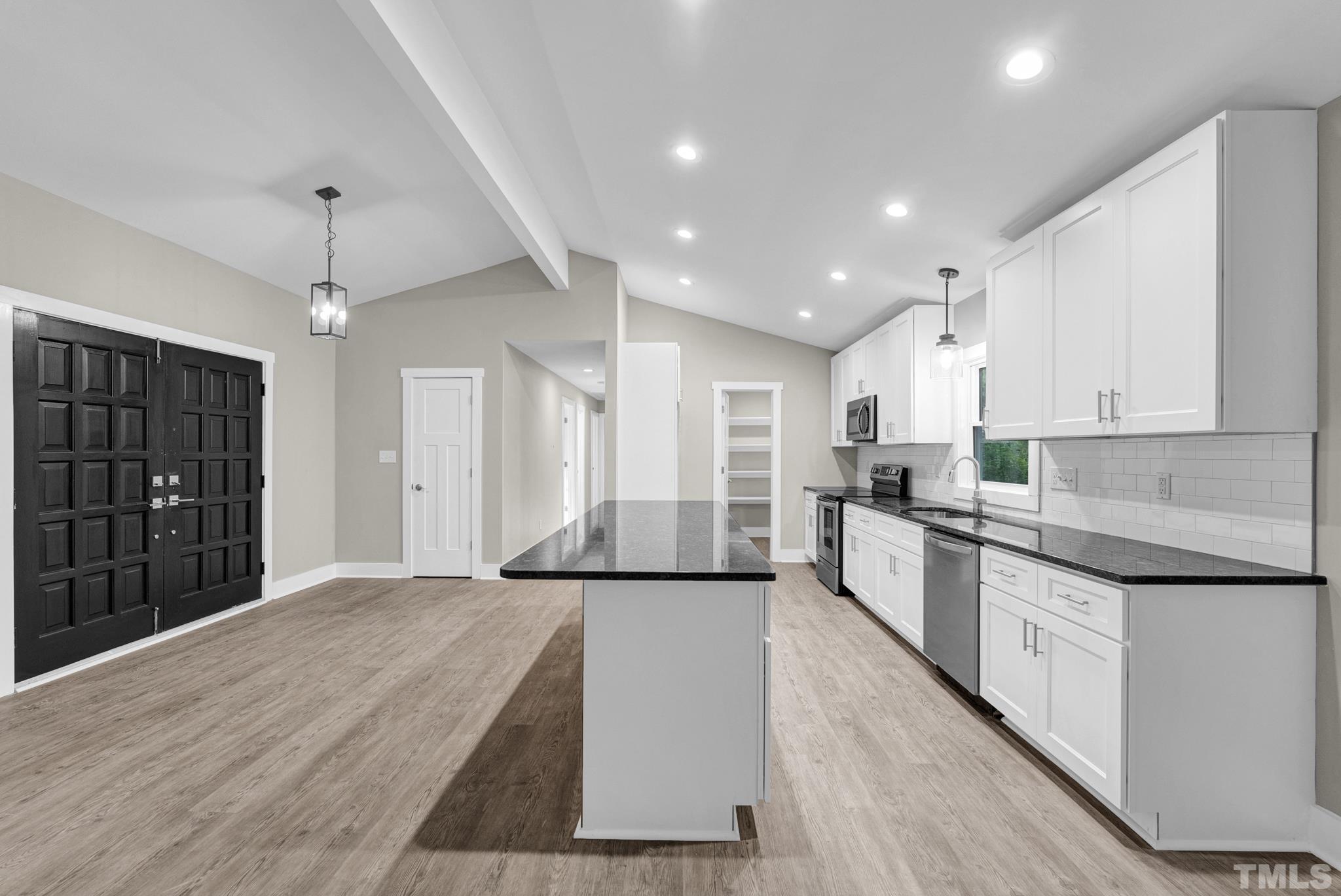 6712 Millbridge Court Raleigh, NC 27615 - Photo 8 of 25 a large kitchen with kitchen island a sink stainless steel appliances and cabinets