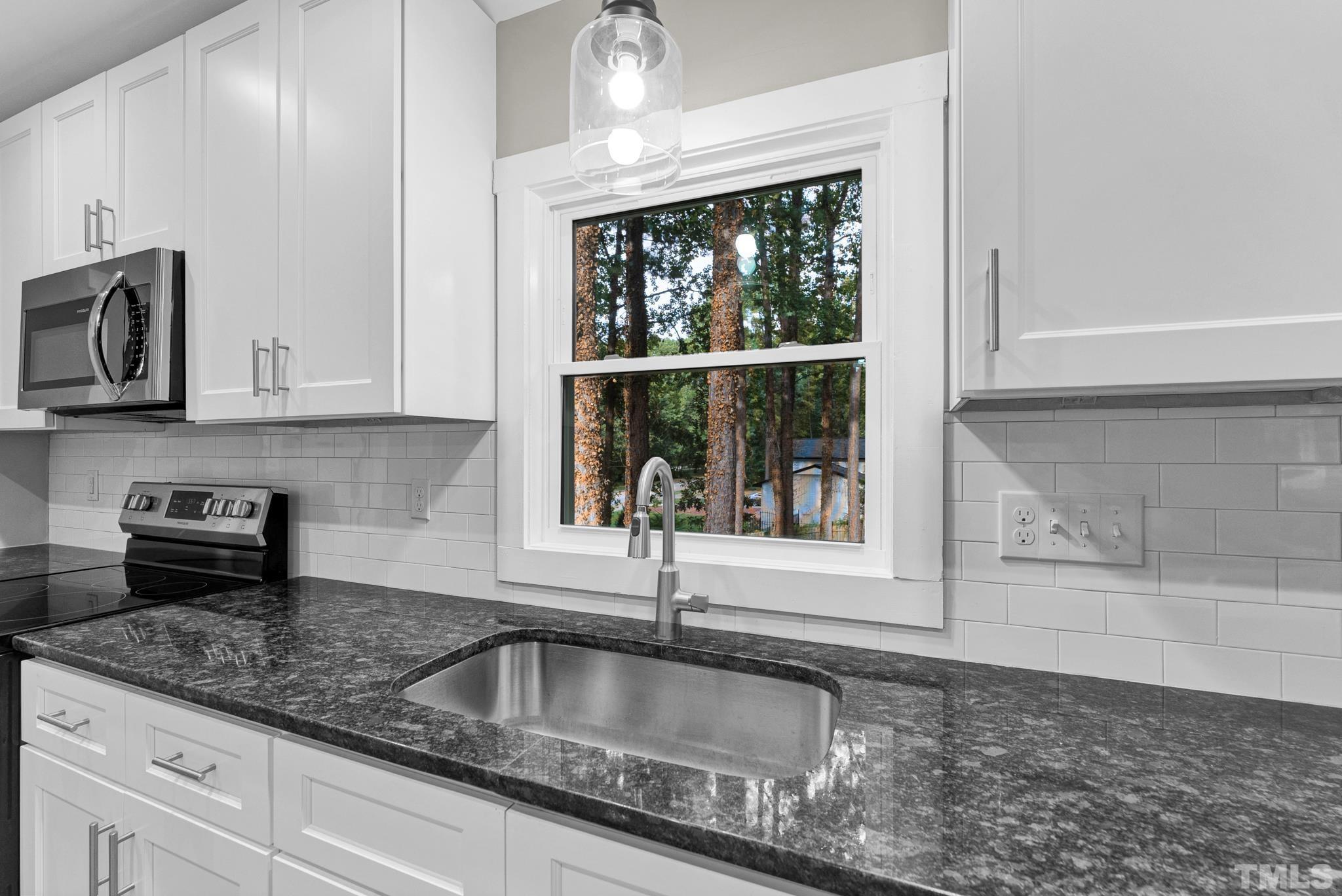 6712 Millbridge Court Raleigh, NC 27615 - Photo 9 of 25 a kitchen with granite countertop a sink and a counter top space