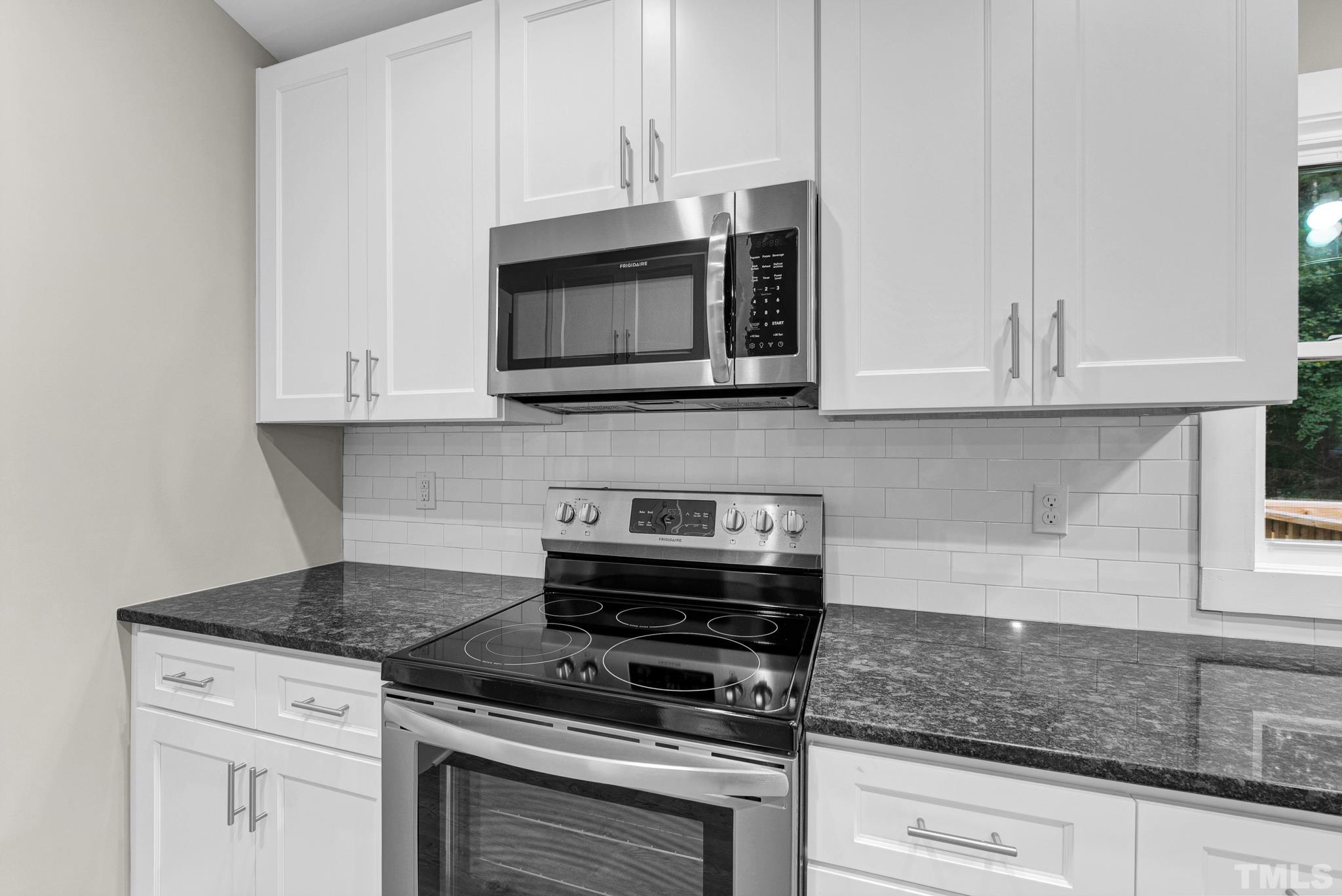 6712 Millbridge Court Raleigh, NC 27615 - Photo 10 of 25 a kitchen with granite countertop white cabinets and appliances