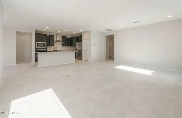 a view of an empty room with kitchen and window