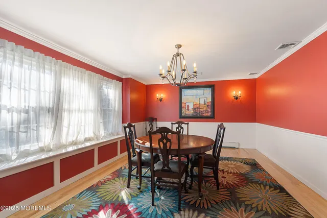 a view of a dining room with furniture a chandelier and wooden floor
