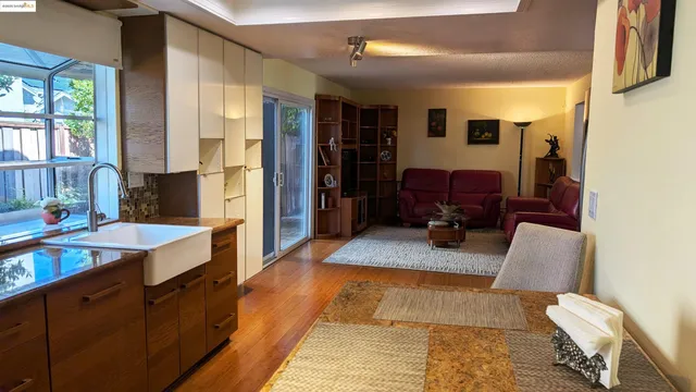 a large living room with stainless steel appliances furniture a window and a kitchen view