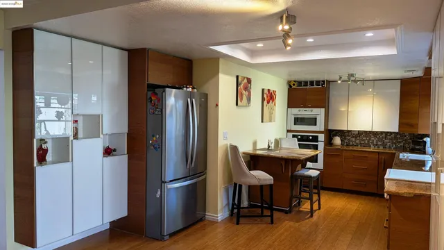 a kitchen with stainless steel appliances granite countertop a refrigerator and a dining table