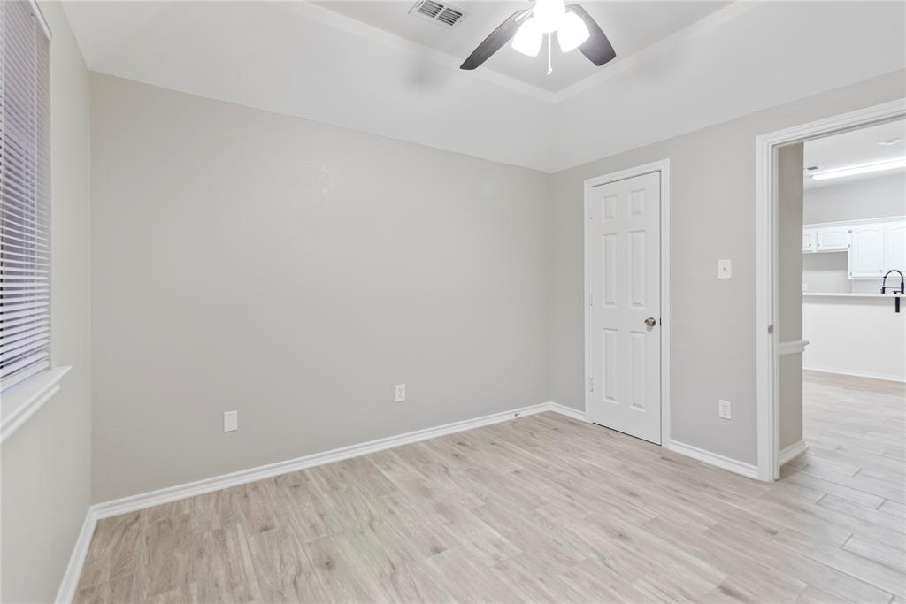 304 Moore Creek Road, Unit 300 Hurst, TX 76053 - Photo 9 of 17 Neutral-toned room featuring light wood-finish flooring, a tray ceiling, and a ceiling fan