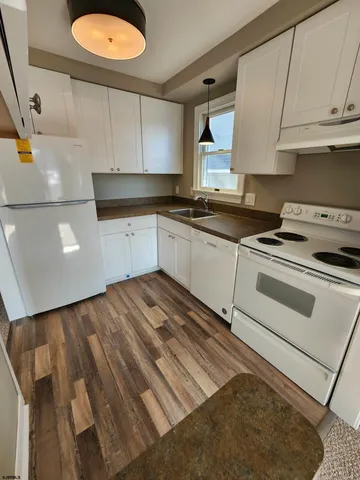 a kitchen with granite countertop white cabinets and white appliances