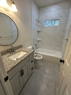 a bathroom with a granite countertop sink a toilet and bathtub
