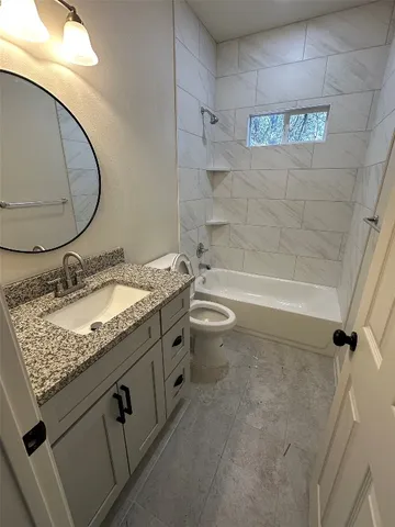 a bathroom with a granite countertop sink a toilet and bathtub
