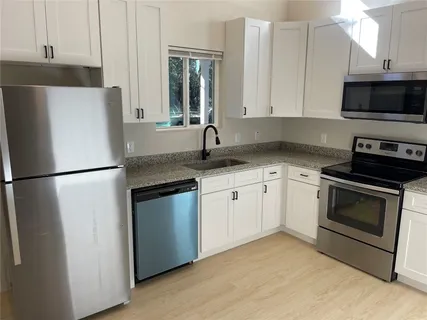 a kitchen with stainless steel appliances granite countertop a refrigerator stove a sink and a microwave