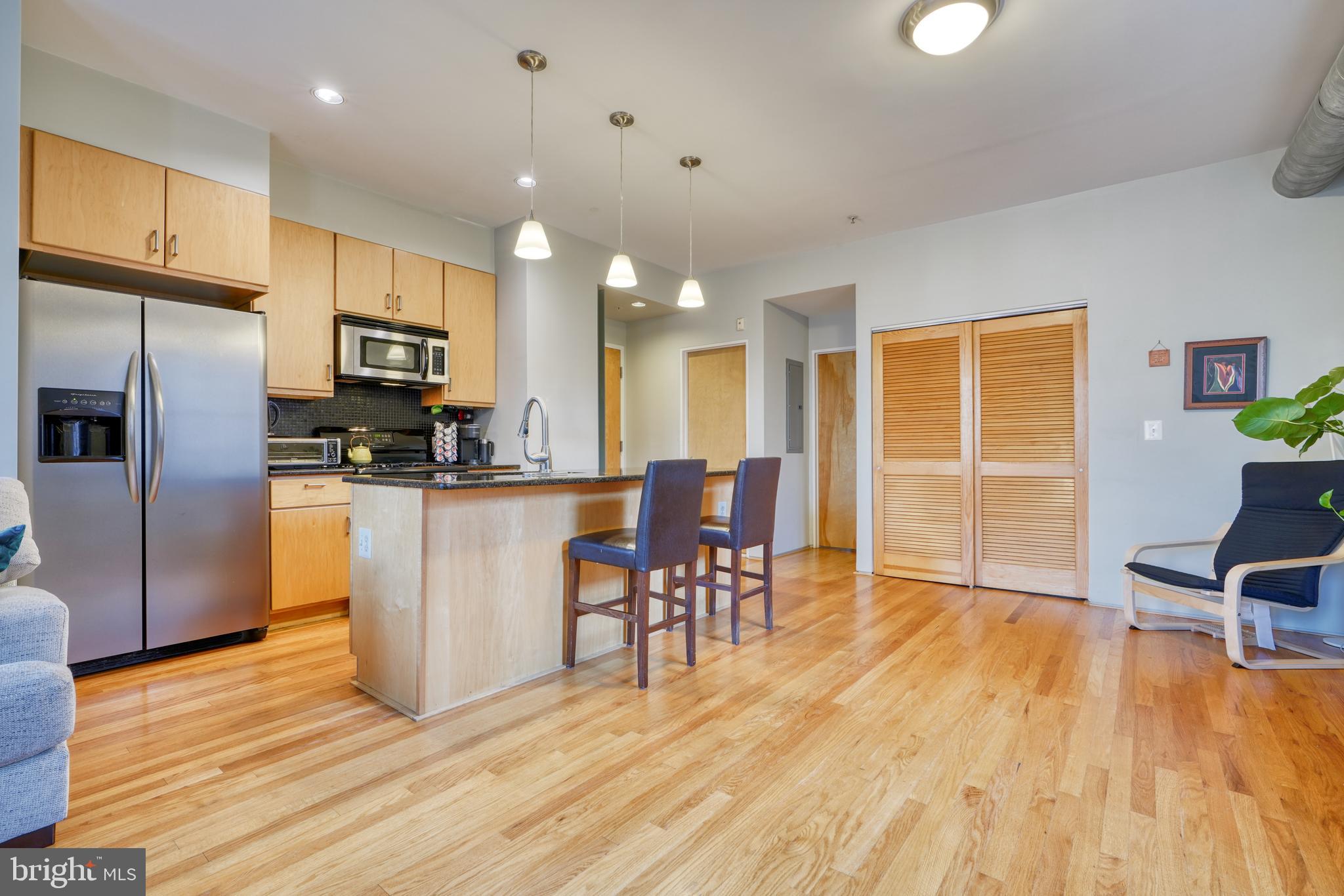 a kitchen with stainless steel appliances a dining table chairs stove refrigerator and cabinets