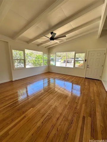 a view of empty room with wooden floor and fan