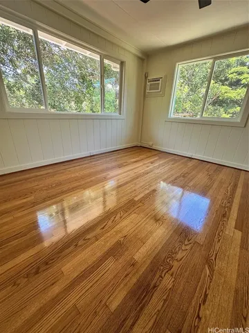 a view of empty room with wooden floor and fan