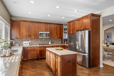 a kitchen with stainless steel appliances granite countertop a refrigerator a sink a stove a washer dryer and cabinets