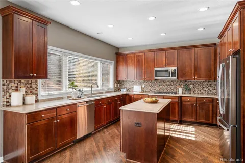a kitchen with stainless steel appliances granite countertop wooden cabinets a sink and a stove
