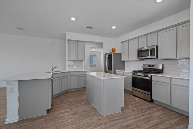 a kitchen with cabinets wooden floor and stainless steel appliances