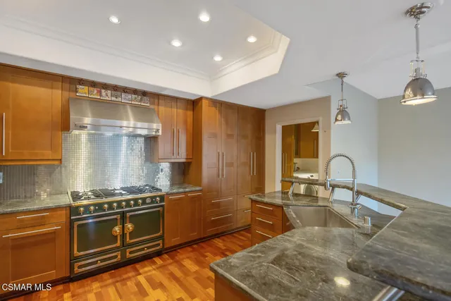 a kitchen with stainless steel appliances granite countertop a stove a sink and a microwave