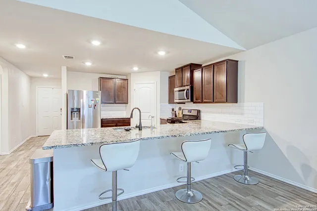a kitchen with stainless steel appliances granite countertop a sink refrigerator and cabinets