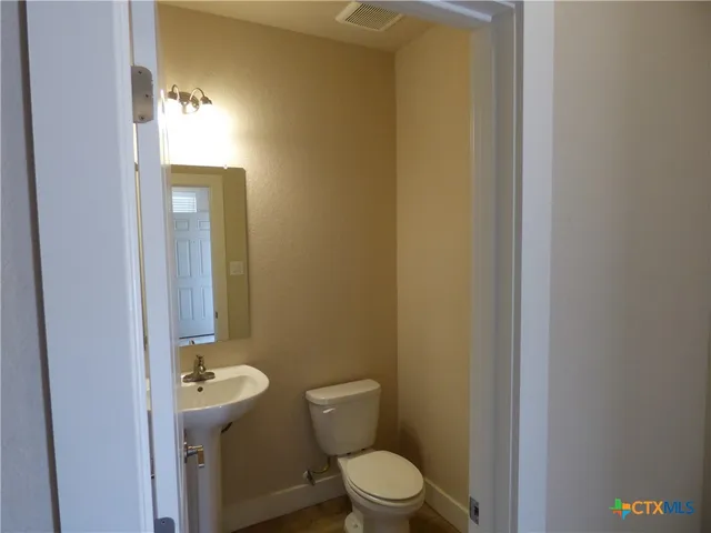 a view of an empty room with wooden floor and a ceiling fan
