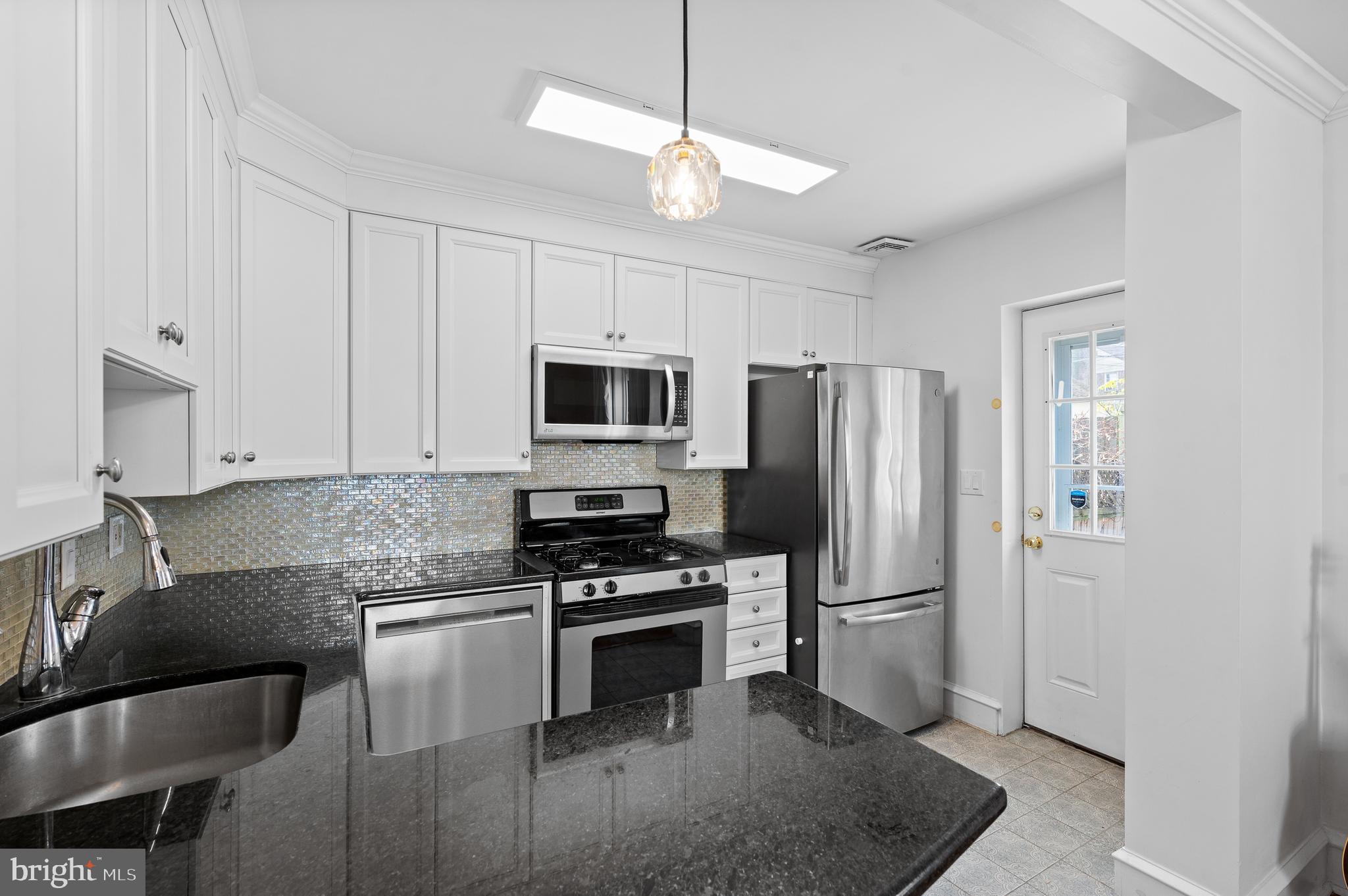 502 Beechwood Lane Narberth, PA 19072 - Photo 12 of 39 a kitchen with granite countertop a refrigerator a stove a microwave and island with wooden floor