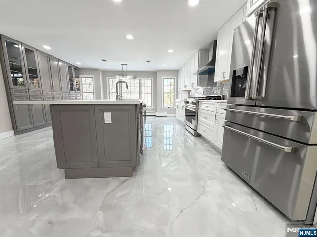 a kitchen with stainless steel appliances granite countertop a refrigerator a sink a stove and oven