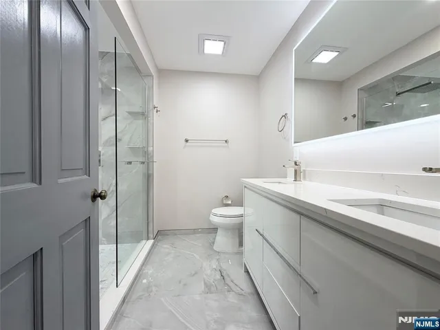 a bathroom with a double vanity sink toilet and shower