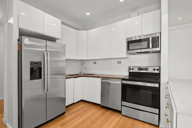 a kitchen with stainless steel appliances granite countertop a sink a stove a refrigerator and white cabinets