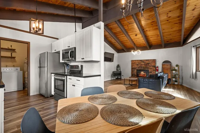 a kitchen with stainless steel appliances granite countertop a sink dishwasher a microwave oven with a dining table and chairs with wooden floor