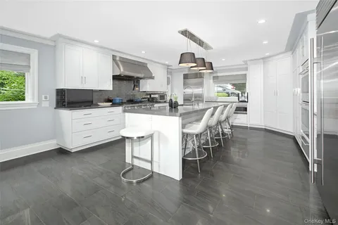 a kitchen with stainless steel appliances a dining table chairs stove refrigerator and cabinets