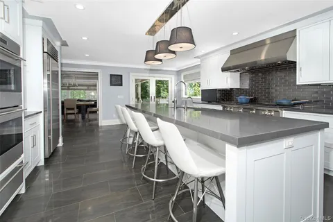 a kitchen with stainless steel appliances granite countertop a table chairs sink and cabinets