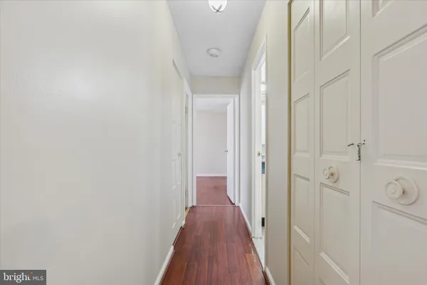 a view of a hallway with wooden floor and a shower
