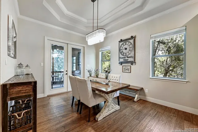 a dining room with wooden floor a chandelier a wooden table and chairs