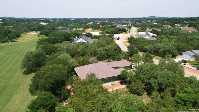 an aerial view of residential houses with outdoor space and trees