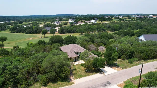 an aerial view of residential houses with outdoor space and trees