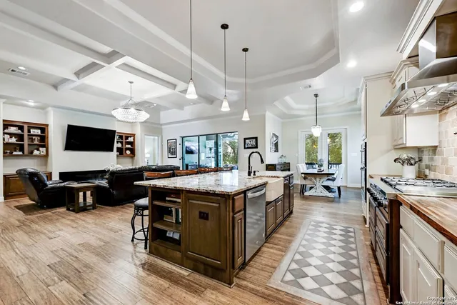 a large kitchen with stainless steel appliances a stove a sink dishwasher a dining table and chairs with wooden floor