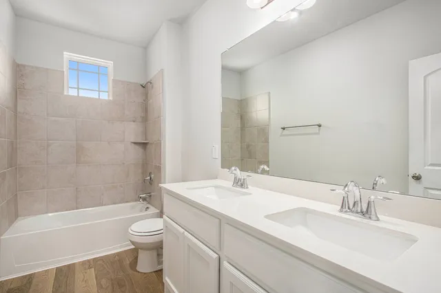 a bathroom with a bathtub shower sink vanity mirror and toilet