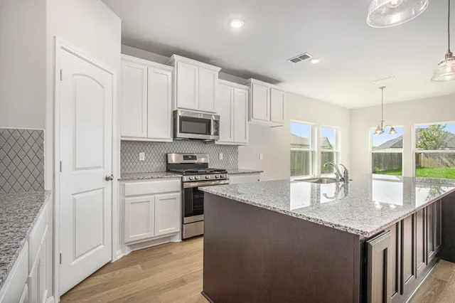 a kitchen with stainless steel appliances granite countertop a stove a sink and a refrigerator