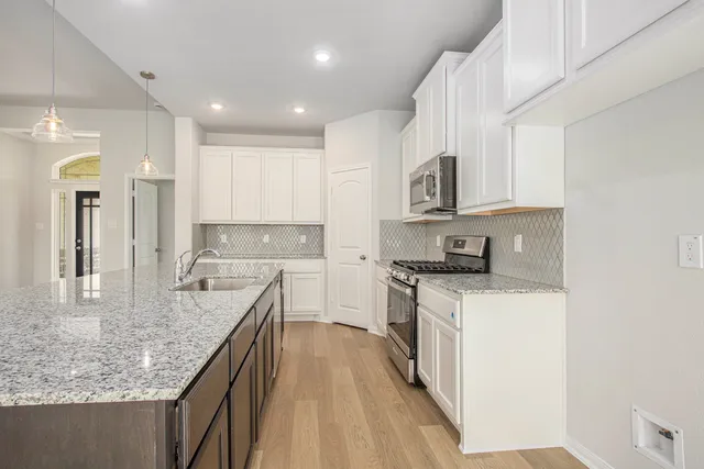 a kitchen with stainless steel appliances granite countertop a sink stove and refrigerator