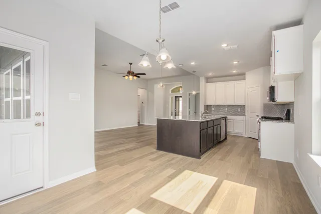 a large kitchen with a refrigerator a stove top oven and a sink