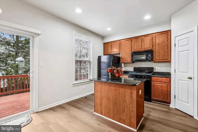 a kitchen with kitchen island granite countertop a stove top oven a sink dishwasher and a refrigerator with wooden cabinets