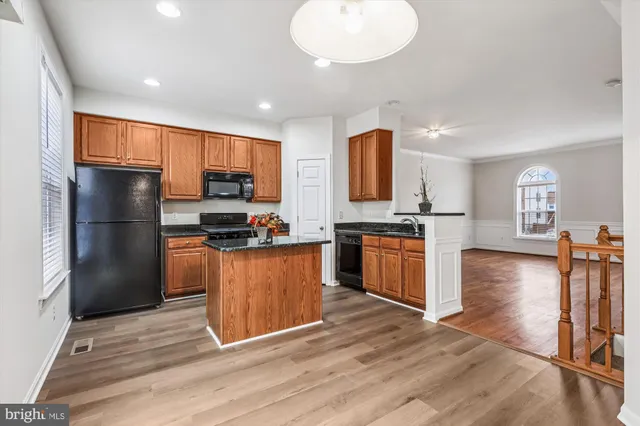 a kitchen with stainless steel appliances granite countertop a refrigerator stove top oven and cabinets