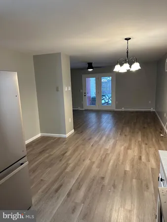 an empty room with wooden floor chandelier and windows