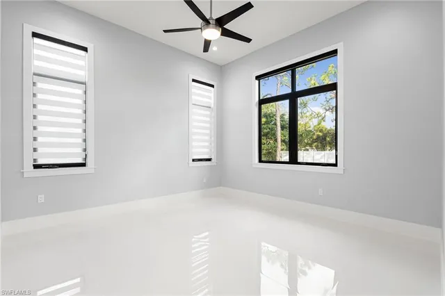 an empty room with windows and fan