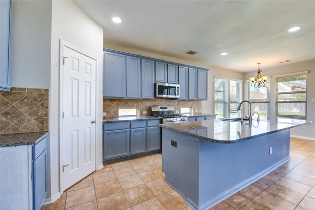 a large kitchen with granite countertop a large counter top stainless steel appliances and cabinets