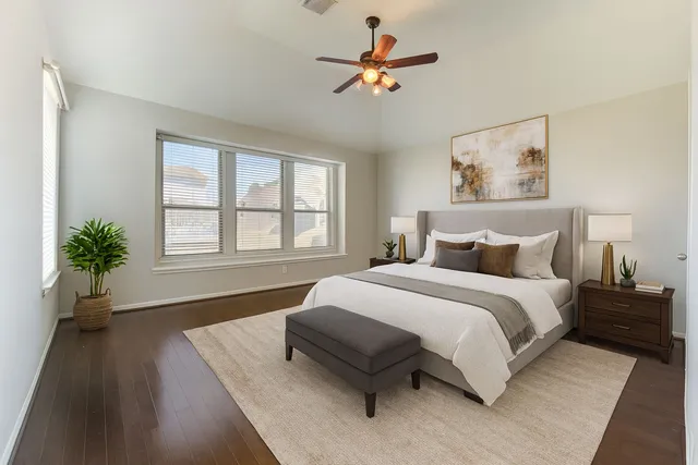a spacious bedroom with a bed a window and a potted plant on a dresser