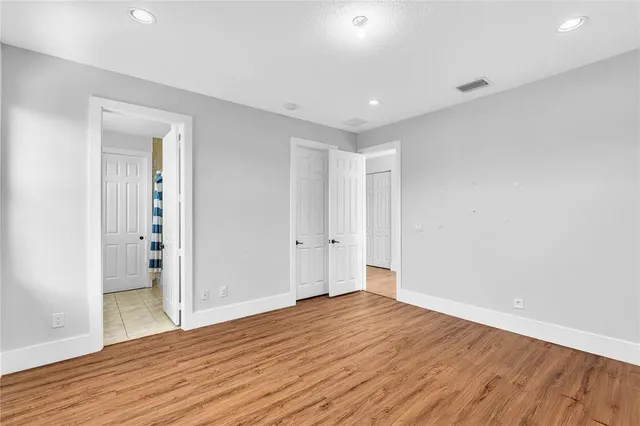 a view of empty room with wooden floor and fan