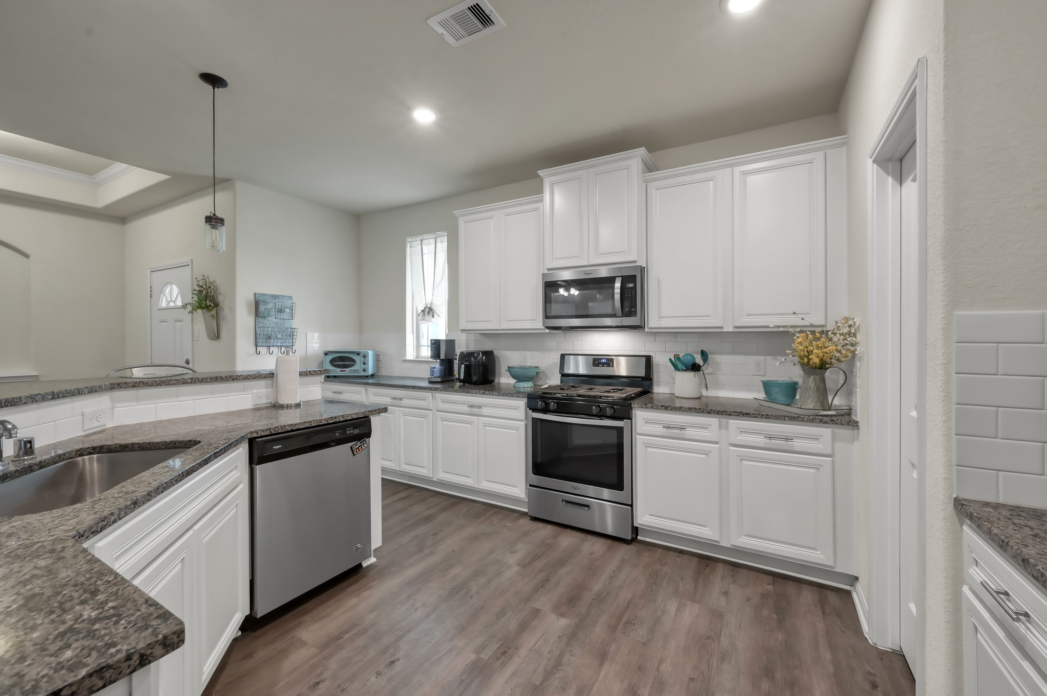 6264 Rolling Hills Road Conroe, TX 77303 - Photo 8 of 24 a kitchen with stainless steel appliances white cabinets a sink a stove a microwave and wooden floors